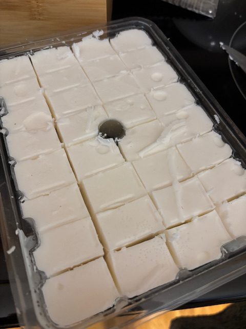A tray of solid white soap base cut into squares, ready for melting and crafting.