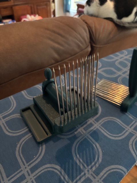 Close-up of wool combs on a patterned blue tablecloth, featuring sharp prongs for fiber preparation.