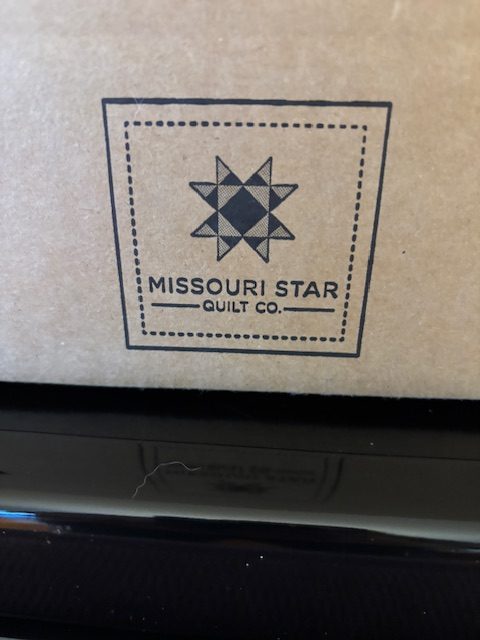 Logo of Missouri Star Quilt Company featuring a star design on a brown background.