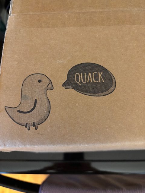 A cartoon bird next to a speech bubble that says 'QUACK', printed on a brown cardboard box.