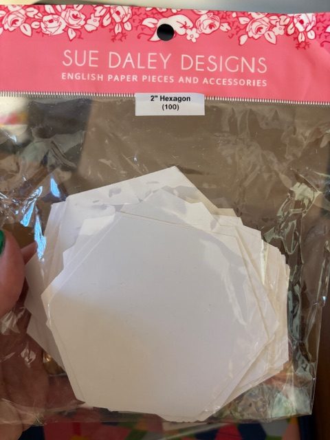 Package of 2-inch hexagon paper pieces by Sue Daley Designs, featuring a clear plastic bag containing multiple blank hexagons.
