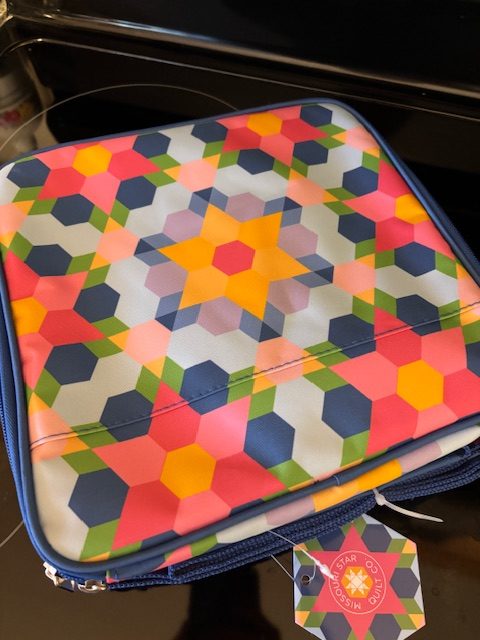Colorful geometric-patterned laptop sleeve featuring hexagons and stars in vibrant shades of pink, blue, green, and yellow.