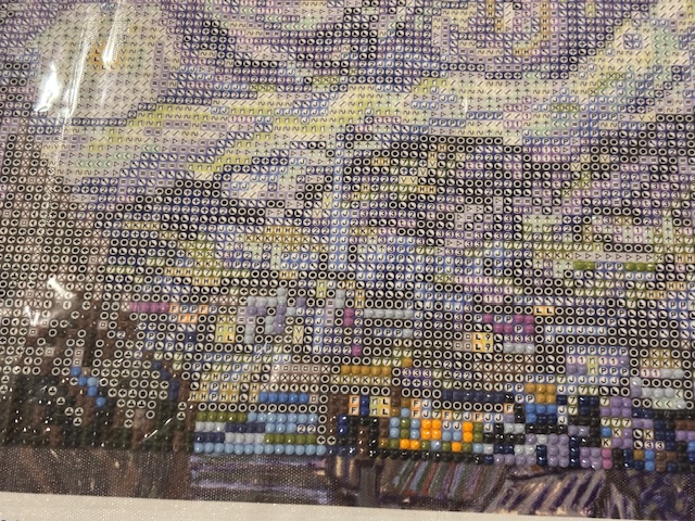 A close-up view of a diamond painting, showcasing intricate details and colorful beads in various shades, depicting a scenic landscape.